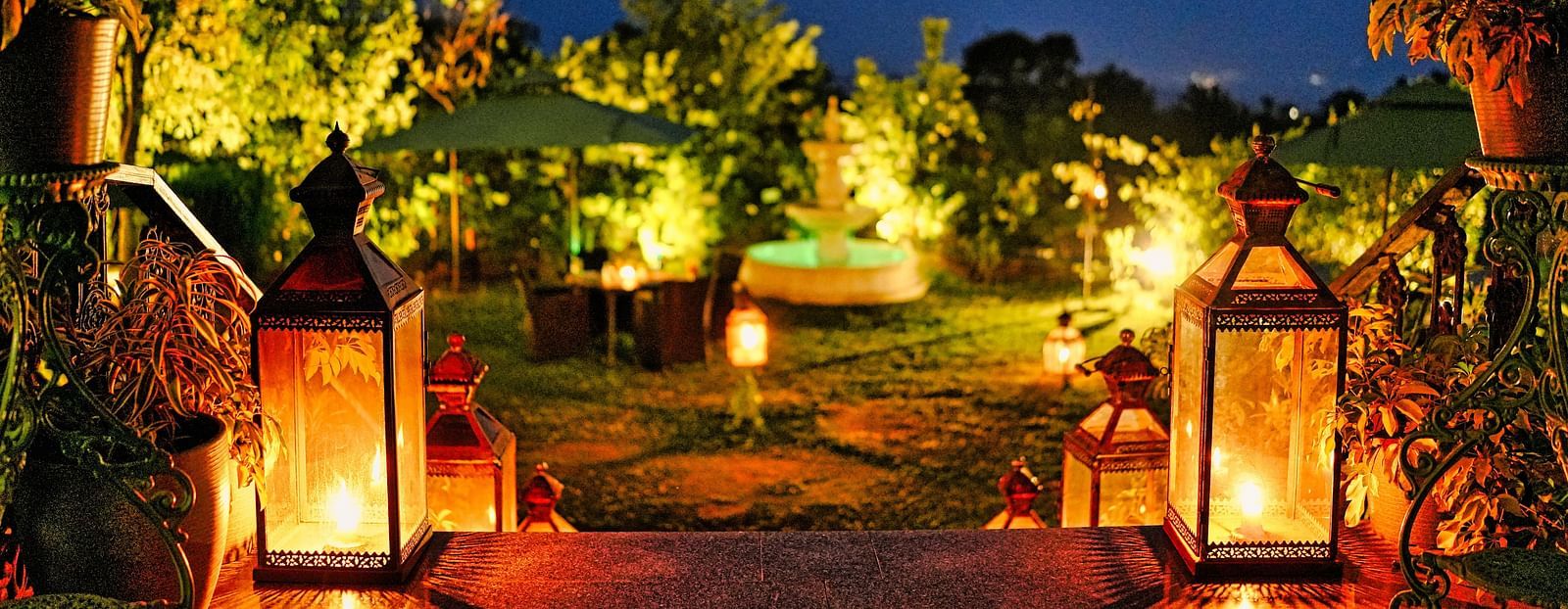 Outdoor dining area with lanterns and string lights lit in the evening - Atman, Dharamshala