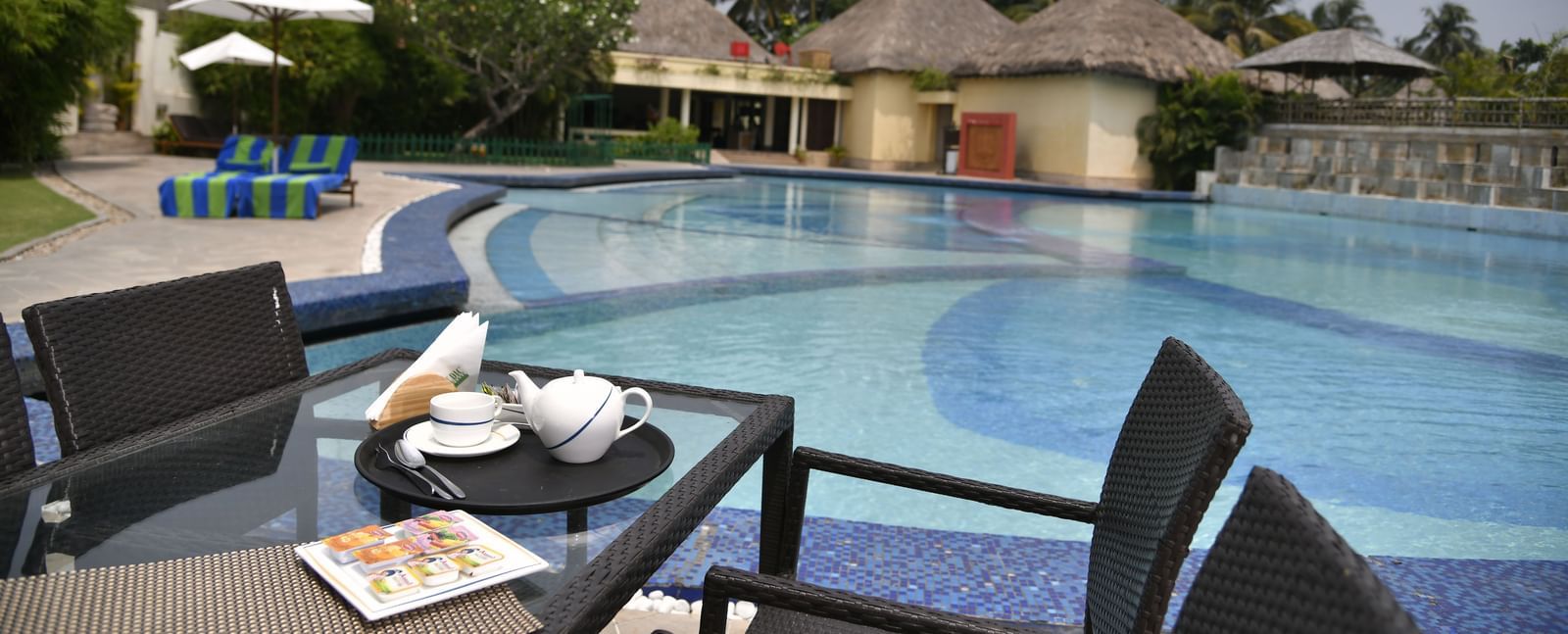A table with food and drinks next to a swimming pool at Vedic Village Spa Resort.
