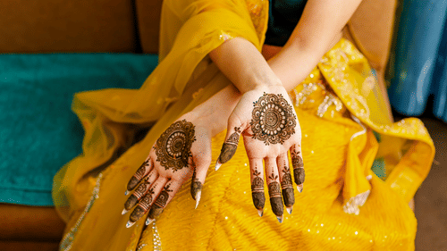 A woman showing her both the palms designed with henna in a Mehndi ceremony
