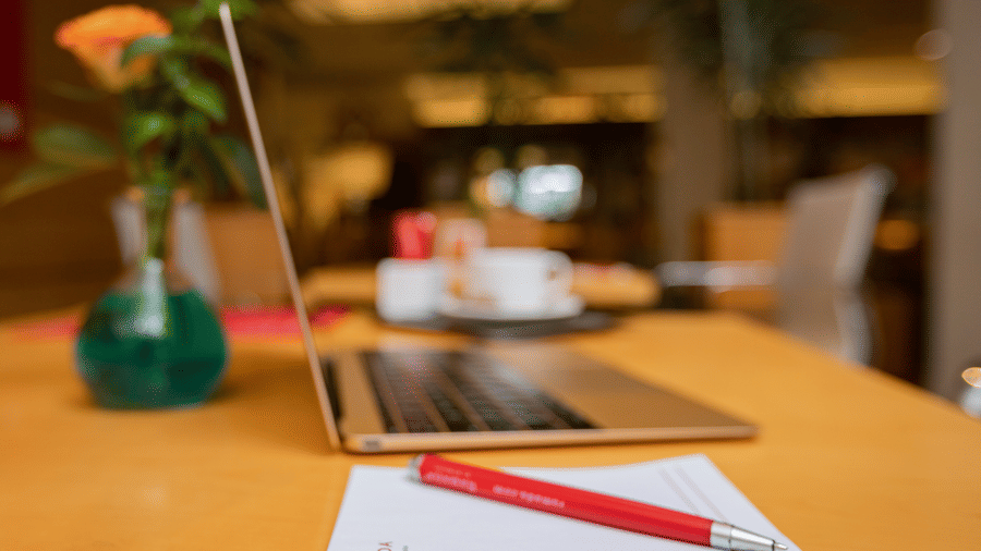 A laptop, notepad, and a flower vase kept on a table at Ramada by Wyndham Addis, featuring the best hotel offers at Ramada by Wyndham Addis, Addis Ababa
