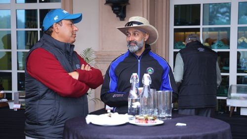 An image of two men talking among themselves in front of a table where food is placed at Heritage Village Resorts & Spa
