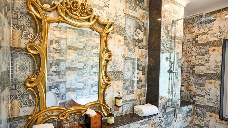 A mirror with decorative framing and essentials arranged below it at Mayfair Manor, Alibag