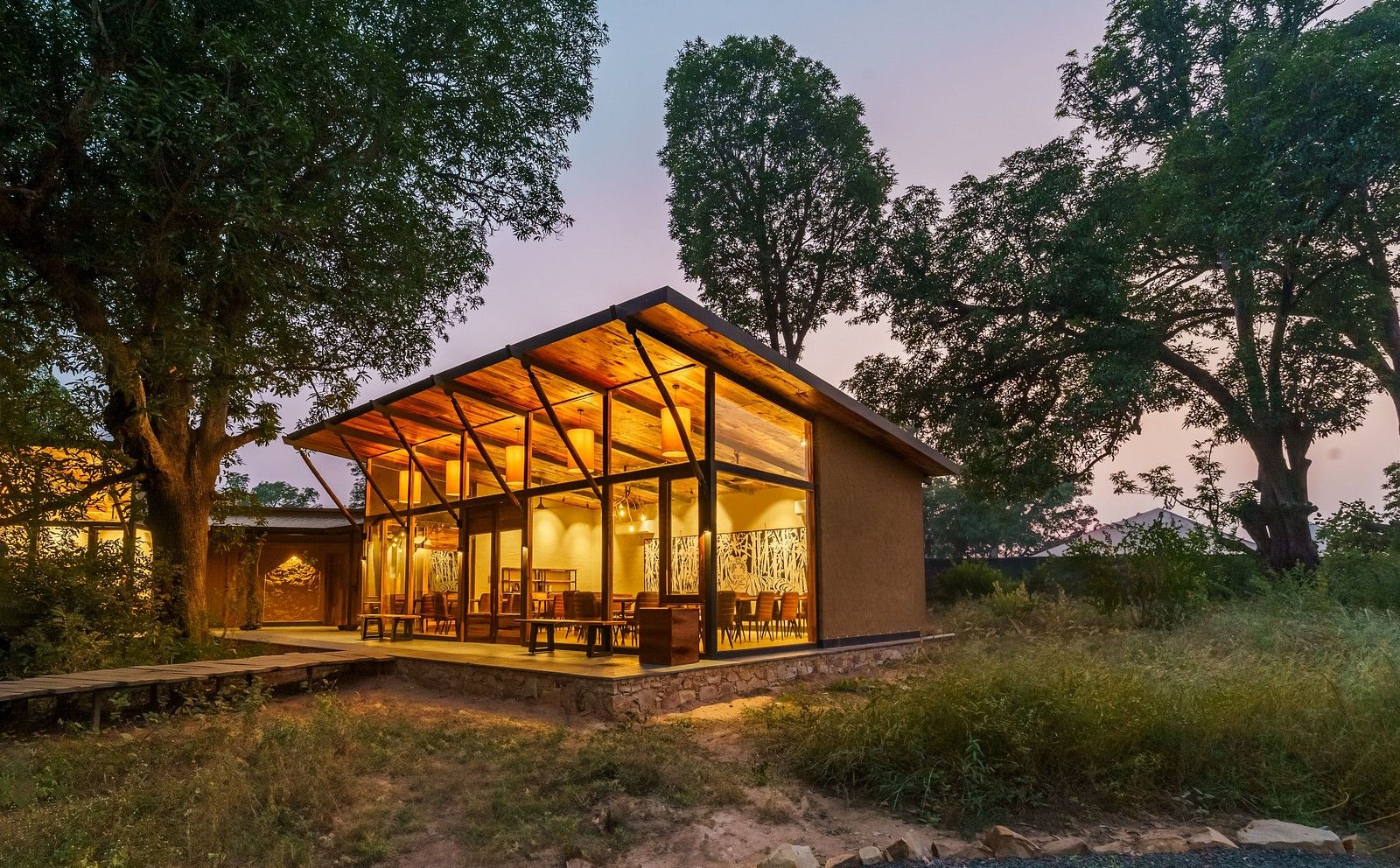 Facade view of a well lit cottage surrounded by trees at Trees N Tigers, Tadoba.