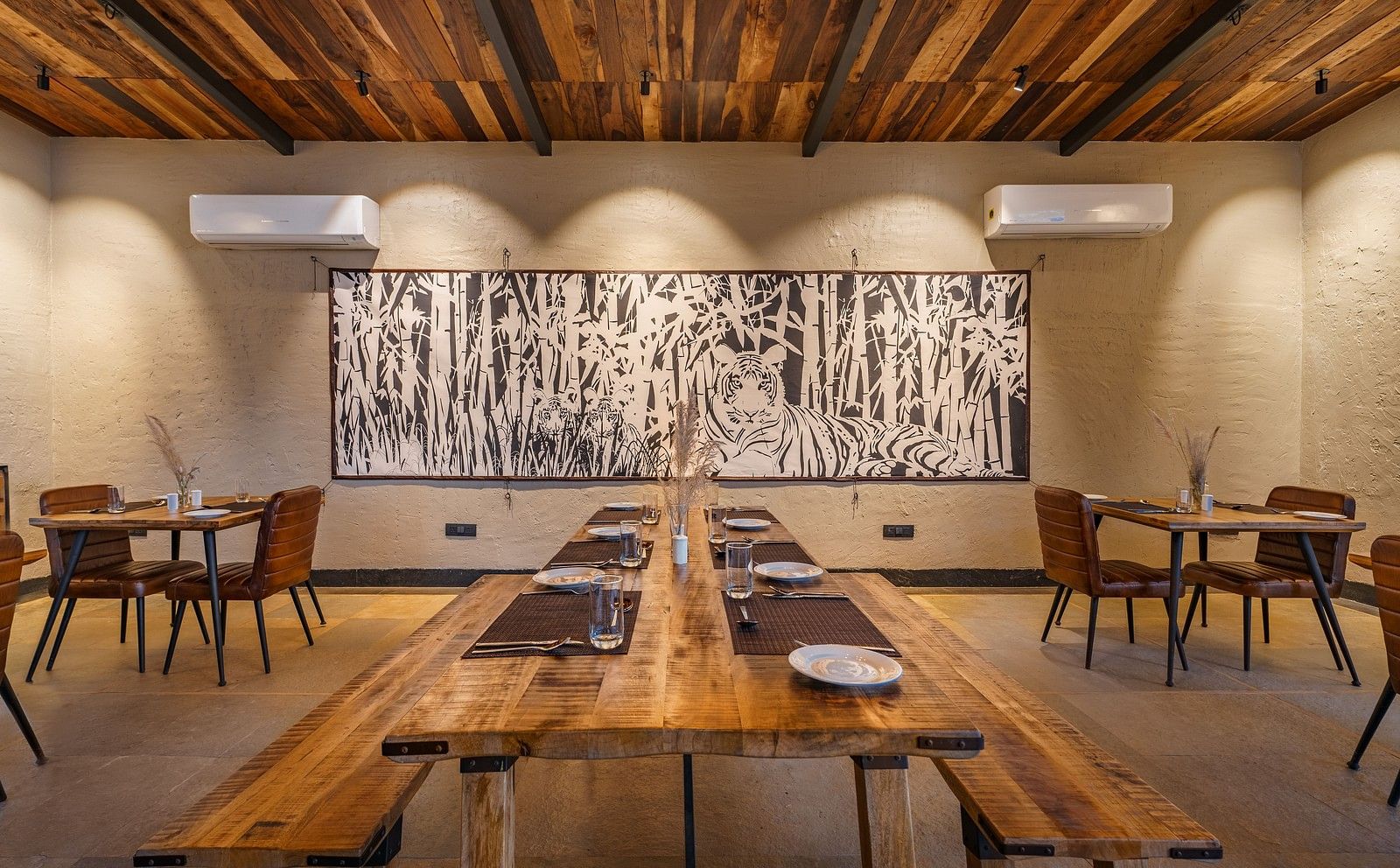 A wide view of a dining area with wooden table, benches and chairs at Trees N Tigers, Tadoba.