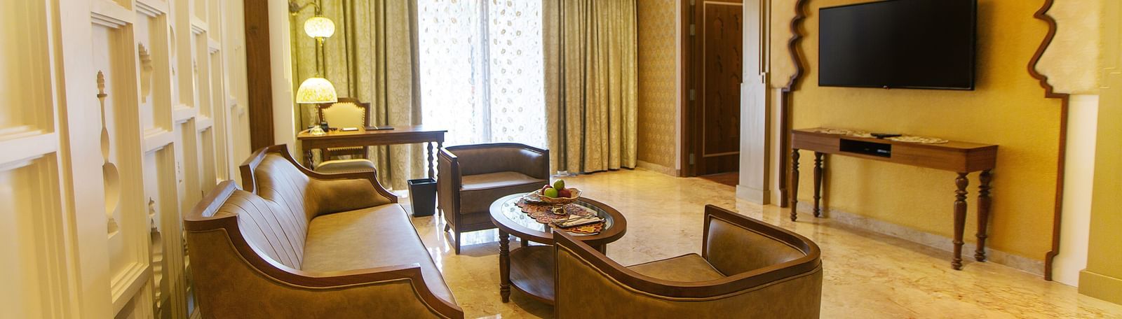 The living room of Executive Palace Suite featuring a coffee table surrounded by couches, a television, and a wall-mounted flat screen television - Kaldan Samudhra Palace