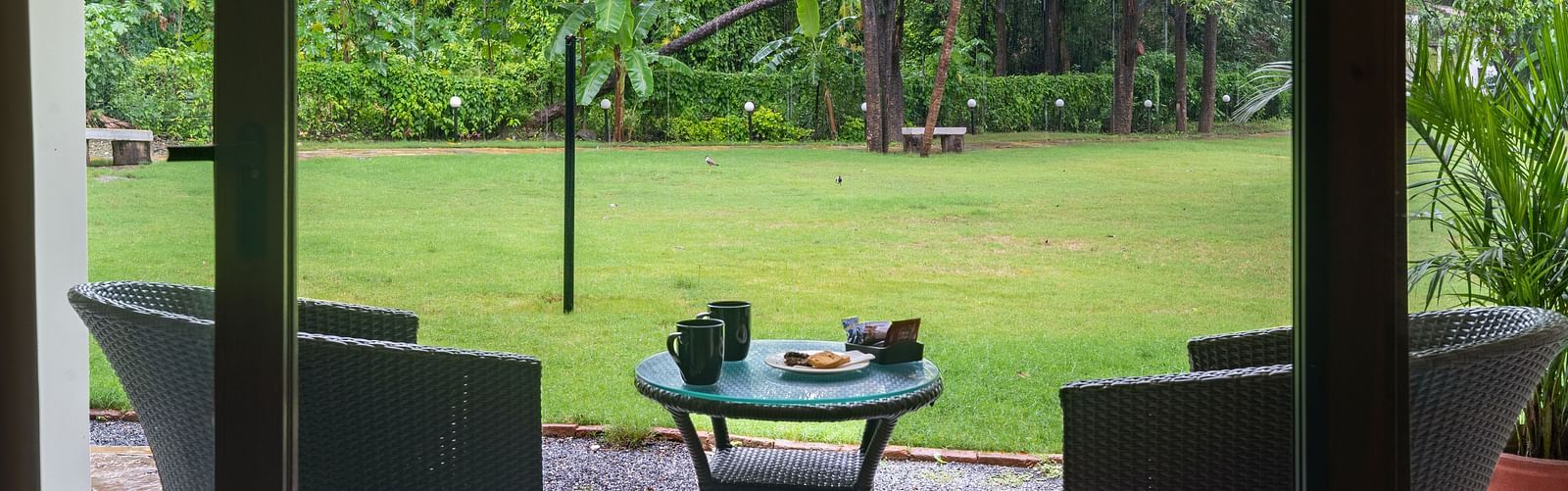 close up image of the private sit out area featuring a green laen with two arm chairs and a coffee table at the luxury family suite at aranya vilas in udaipur