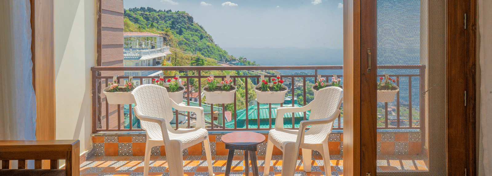 Balcony of the Suite at Perfectstayz Premium Mokshada Suites, Mussoorie, as seen from the inside of the suite, highlighting the outdoor seating area, and peaceful views of the surrounding landscapes.