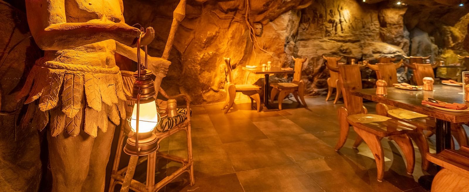 An image of cave themed restaurant with a few sets of chairs and table - The Presidet Hotel, Hubli