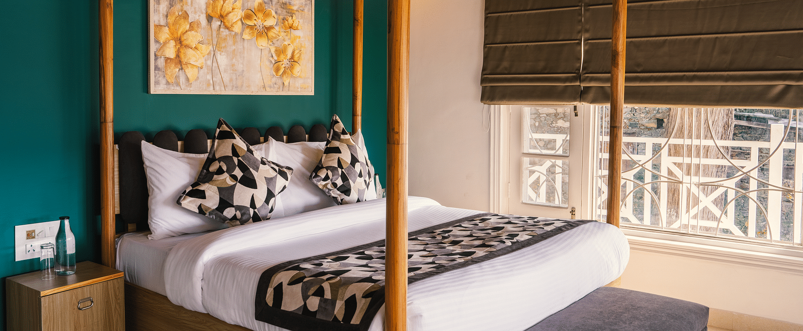 A spacious bed with a wooden frame, a photo frame above the headboard, and a half-closed window to the side at BluSalzz Villas - The Green Roof, Bhimtal.