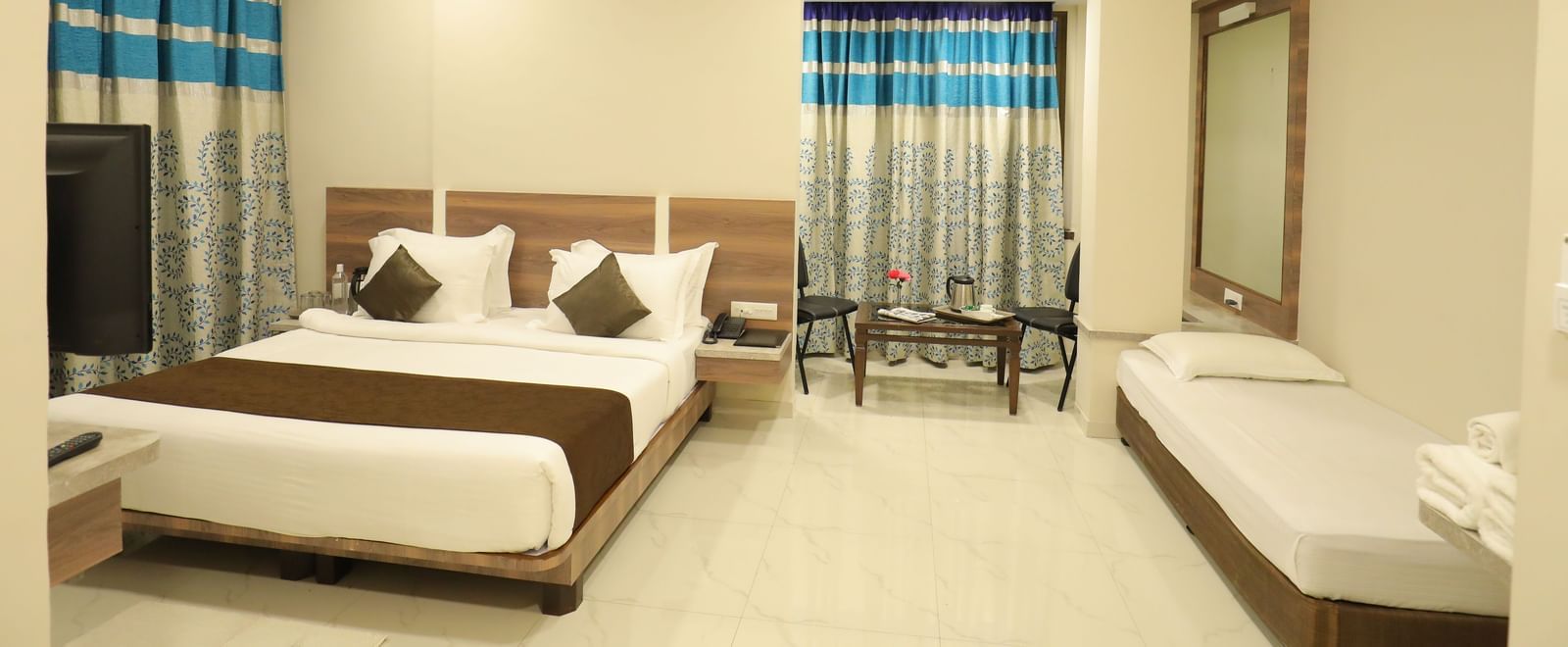 Front view of the Suite of Highland Resort featuring a king size bed, a single bed, a private seating area, and a wall-mounted TV.
