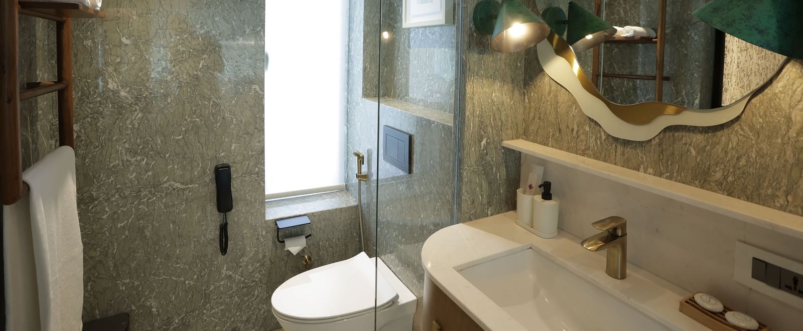 Elegant bathroom interior at Regency Hotel, Mumbai showcasing marble walls, modern fixtures, artistic lighting and premium toiletries for guest comfort.