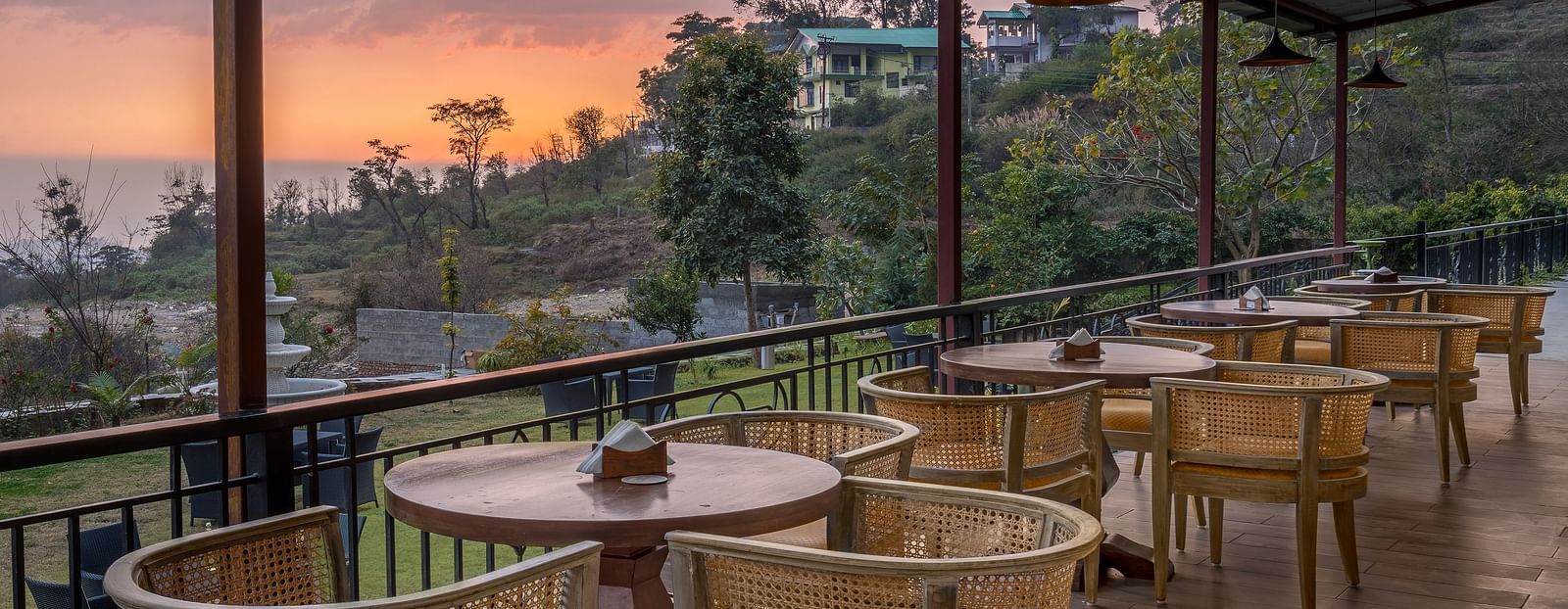 An image of Outdoor seating area with a view of lush trees and mountains at Atman, dharamshala.