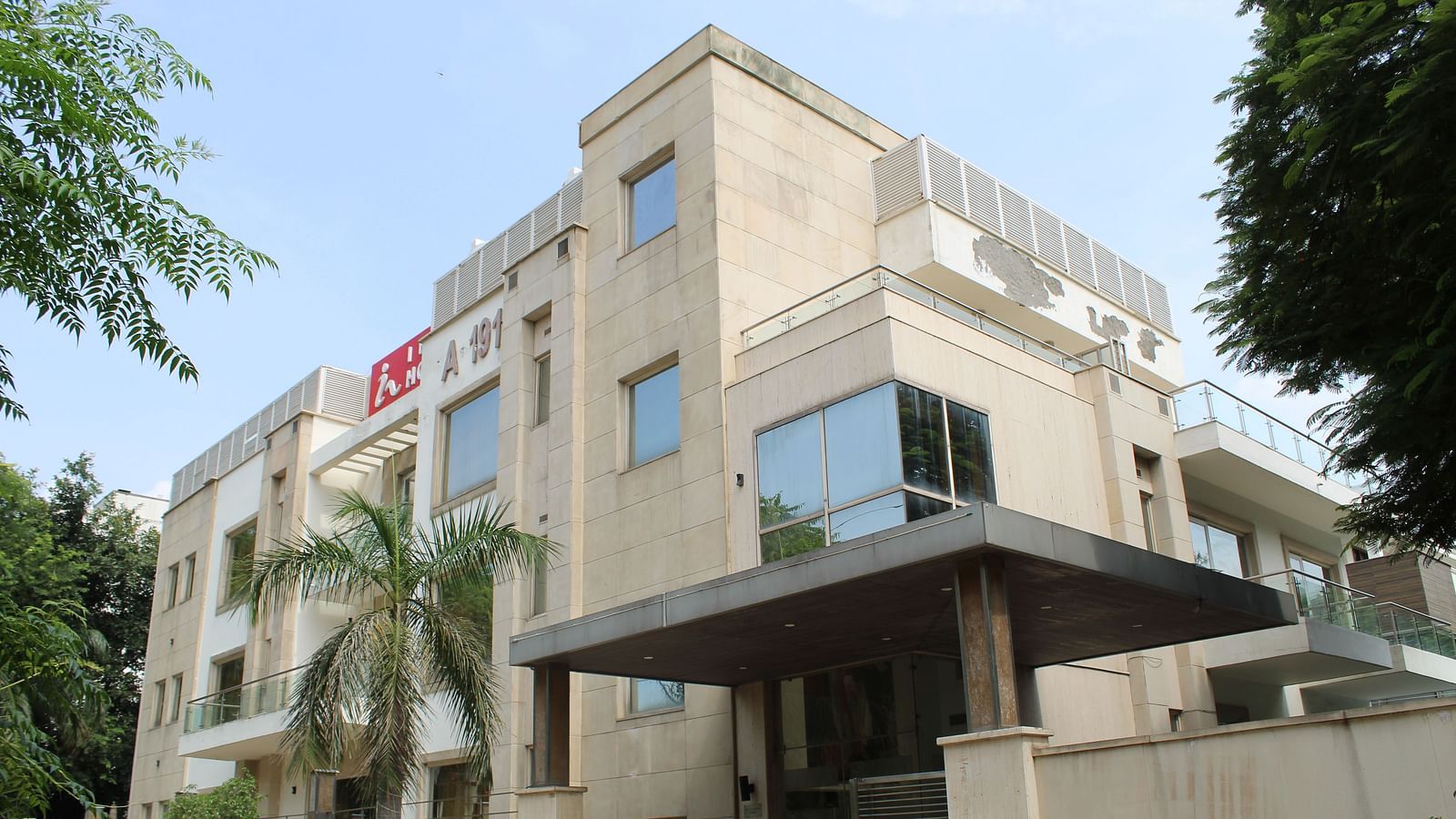 A facade image of Inde Hotels Vista Woods featuring a multi storey building surrounded by trees