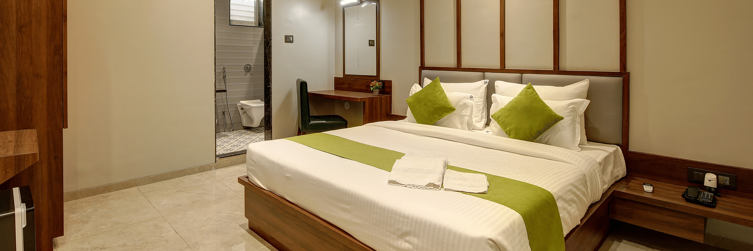 A double bed with an ac wall mounted next to it inside Classic AC Room - Fortune House, Magarpatta
