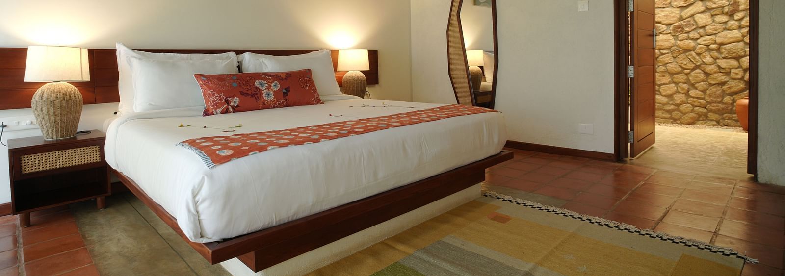  A well-appointed bedroom at Vaasta Vagamon featuring a large bed, bedside tables with lamps, a floor-length mirror, and artwork.
