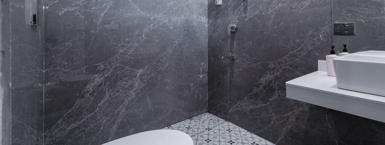 Shower area with grey tiles and rain shower-head at Hotel Downtown17, Chandigarh.