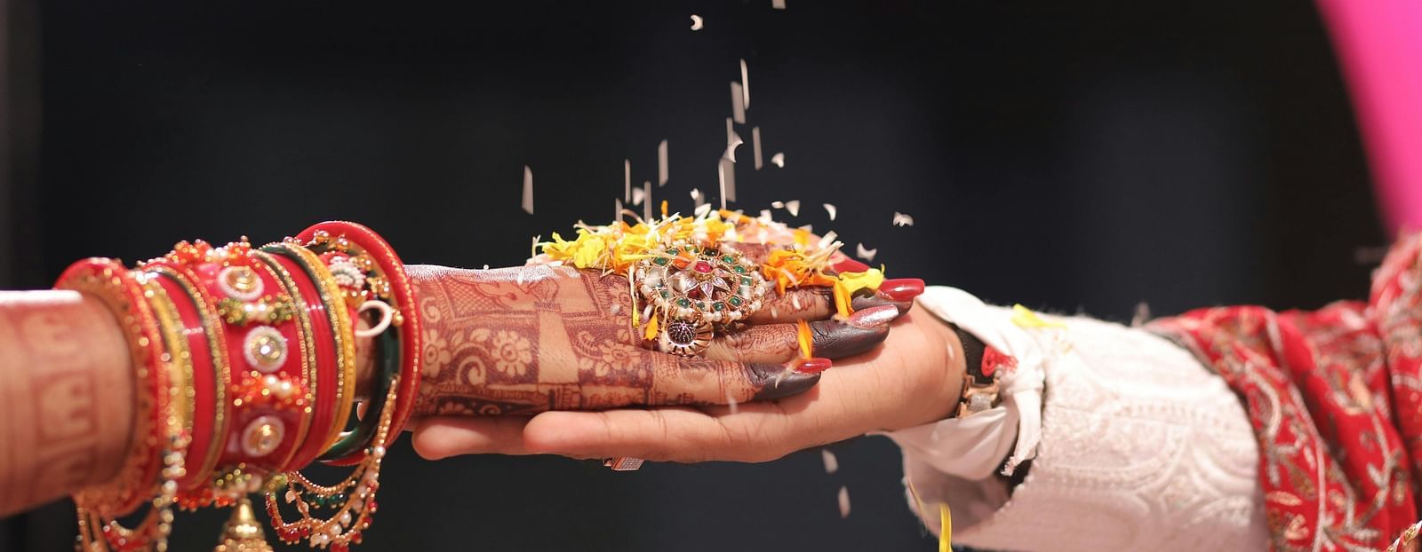 Close-up of hands during an Indian wedding ritual, with rice grains being poured, symbolizing tradition and blessing.