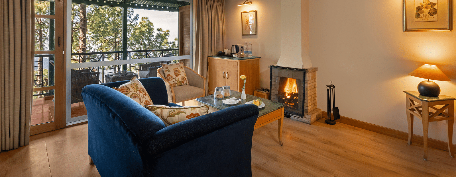 Premium Cottage sitting area with a comfy sofa, a view through window and fireplace in front of sofa at Baikunth resort, kasauli.