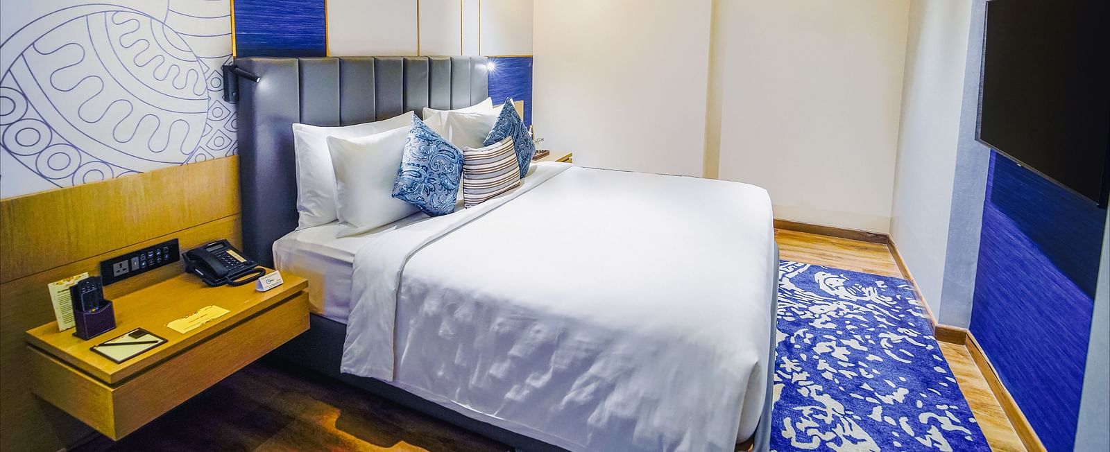An image of our Junior Suite in Madurai with a night stand placed beside a plush bed