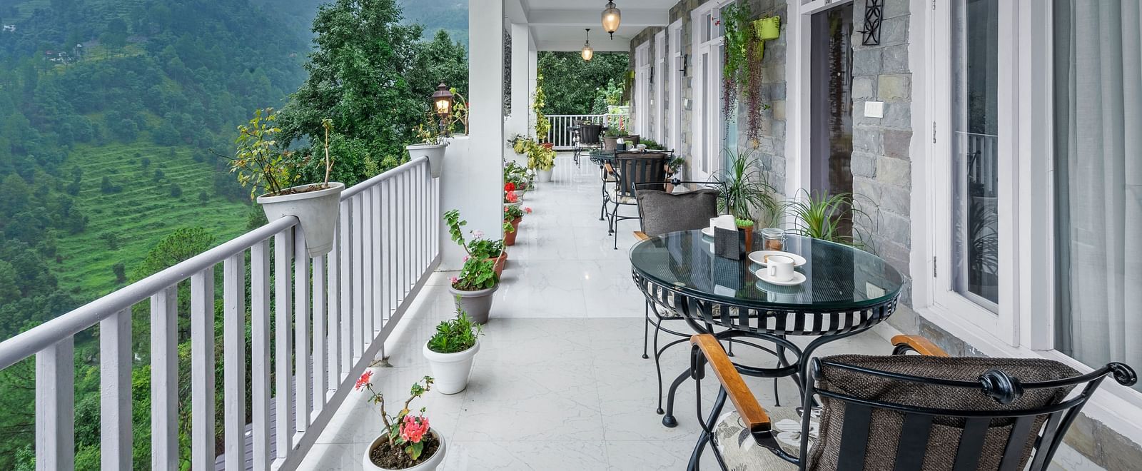 Long verandah with seating arrangements offering panoramic views of the mountains at BluSalzz Collection - Suvaasa Resort, Ramgarh.