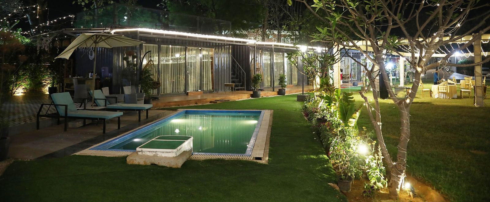 Outdoor venue with swimming pool and night lighting, set up for an event at Tisya Farms, Gurgaon.