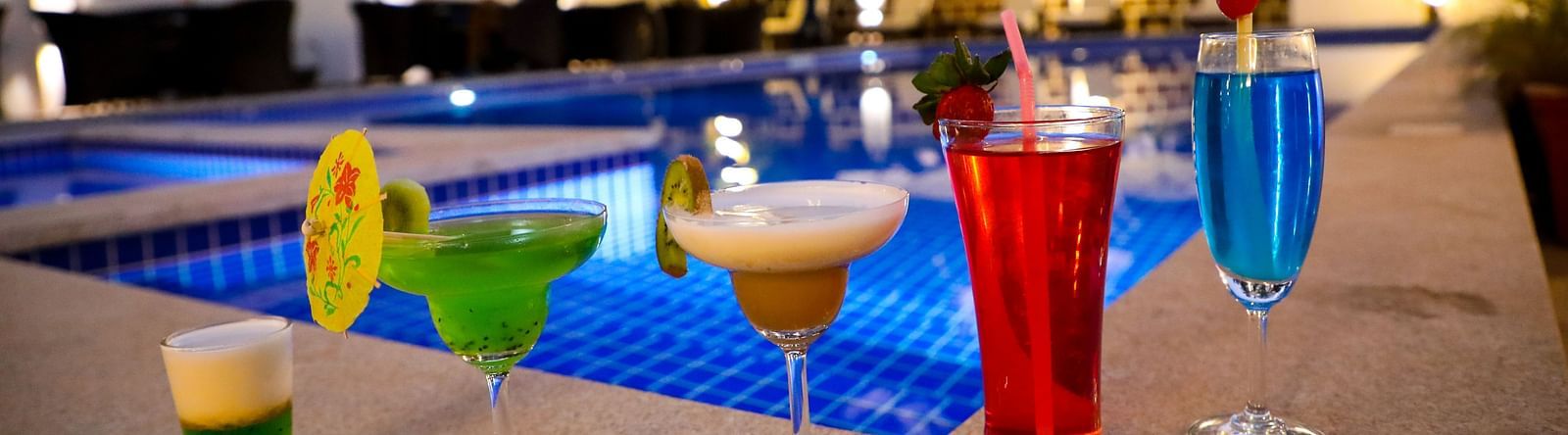 Image of five glasses of drinks placed on the side of a pool at Calux Grand Baga.