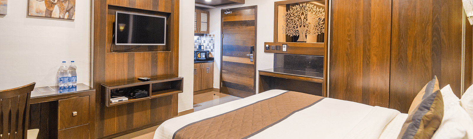 A room with a bed and a wooden wardrobe on the side at Hotel Altitude, Madikeri.