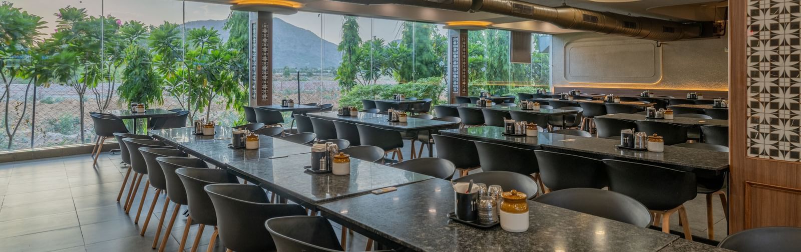 Indoor restaurant seating arrangement with multiple tables and chairs at Hotel Highway King, Neelka.