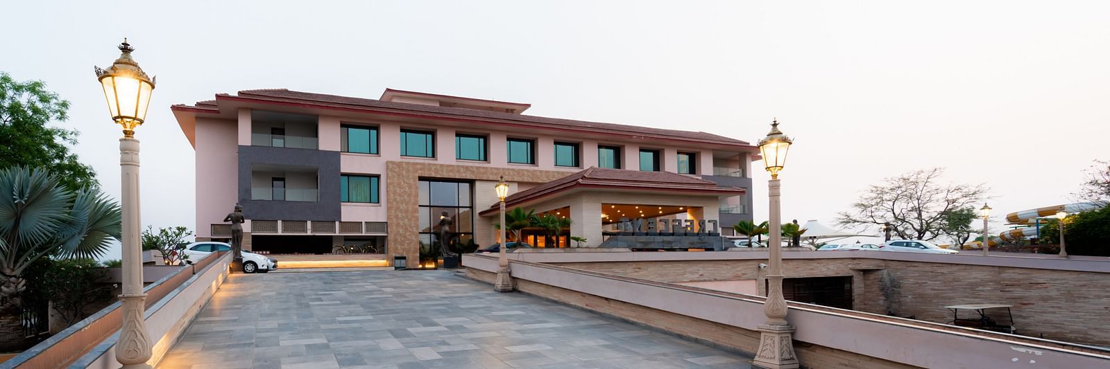 Facade view of Crescent Spa & Resort, Indore, set against a backdrop of a cloudy sky, showcasing its grand architecture