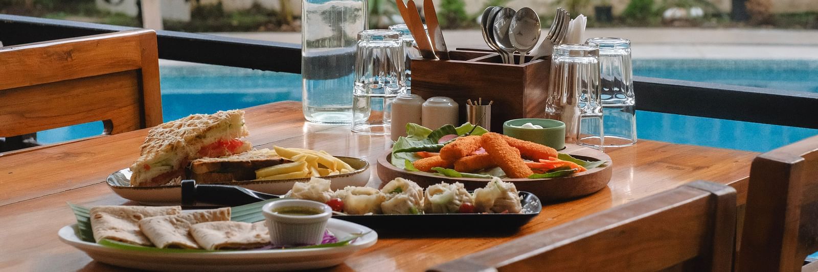 Outdoor dining setup with a variety of dishes beside a pool at The Verda de Miranda Resort.