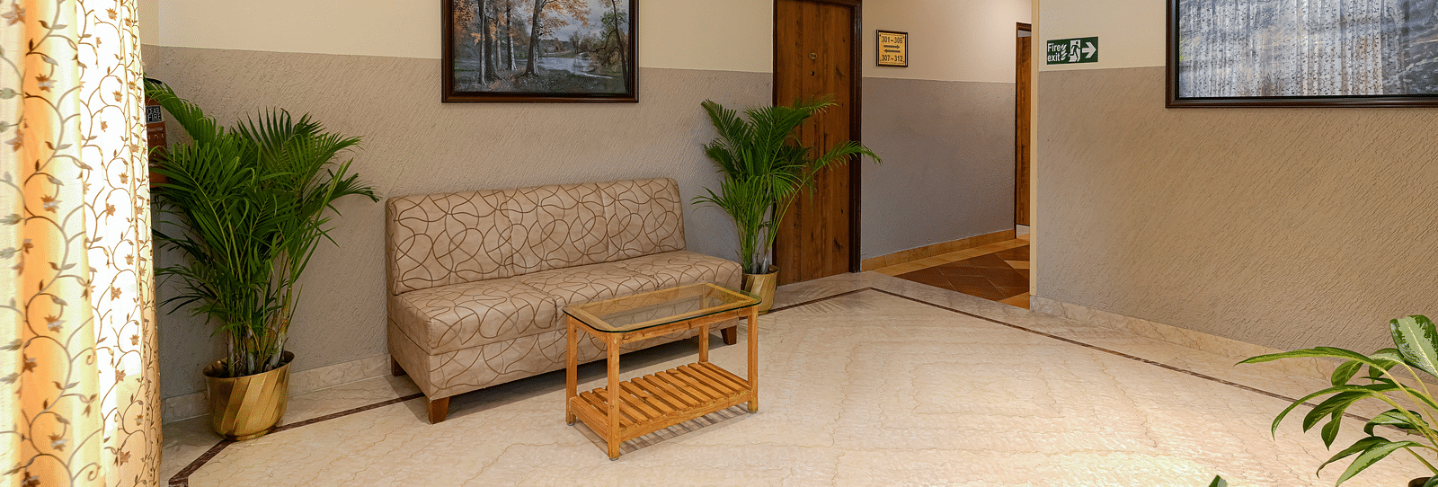 A lobby area with a couch and potted plants - Cross Roads Inn, Bengaluru