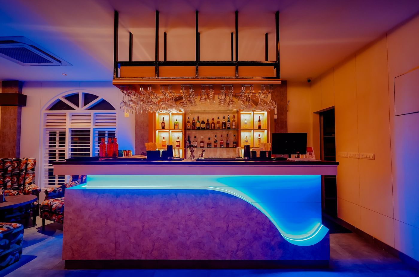 The stylish bar area at Nirantara Resort & Spa, featuring modern lighting, comfortable seating, and a wide selection of beverages.
