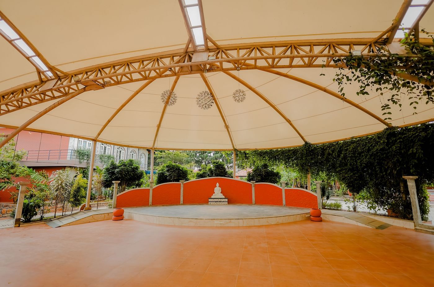 An outdoor event space with a large canopy and a stage at Nirantara Resort & Spa.