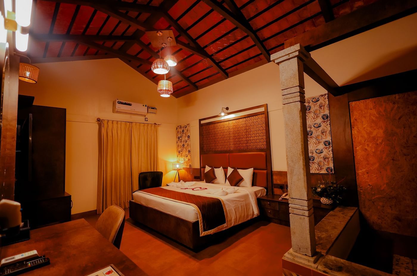 A room with a pitched ceiling and a comfortable bed at Nirantara Resort & Spa.