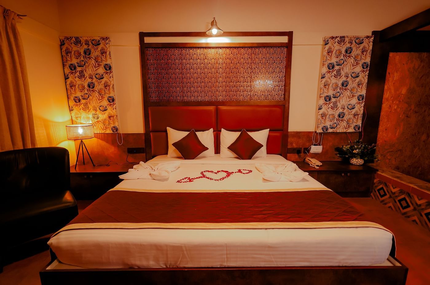 A room with a comfortable bed and warm lighting at Nirantara Resort & Spa, Bengaluru, featuring decorative towels and flowers.