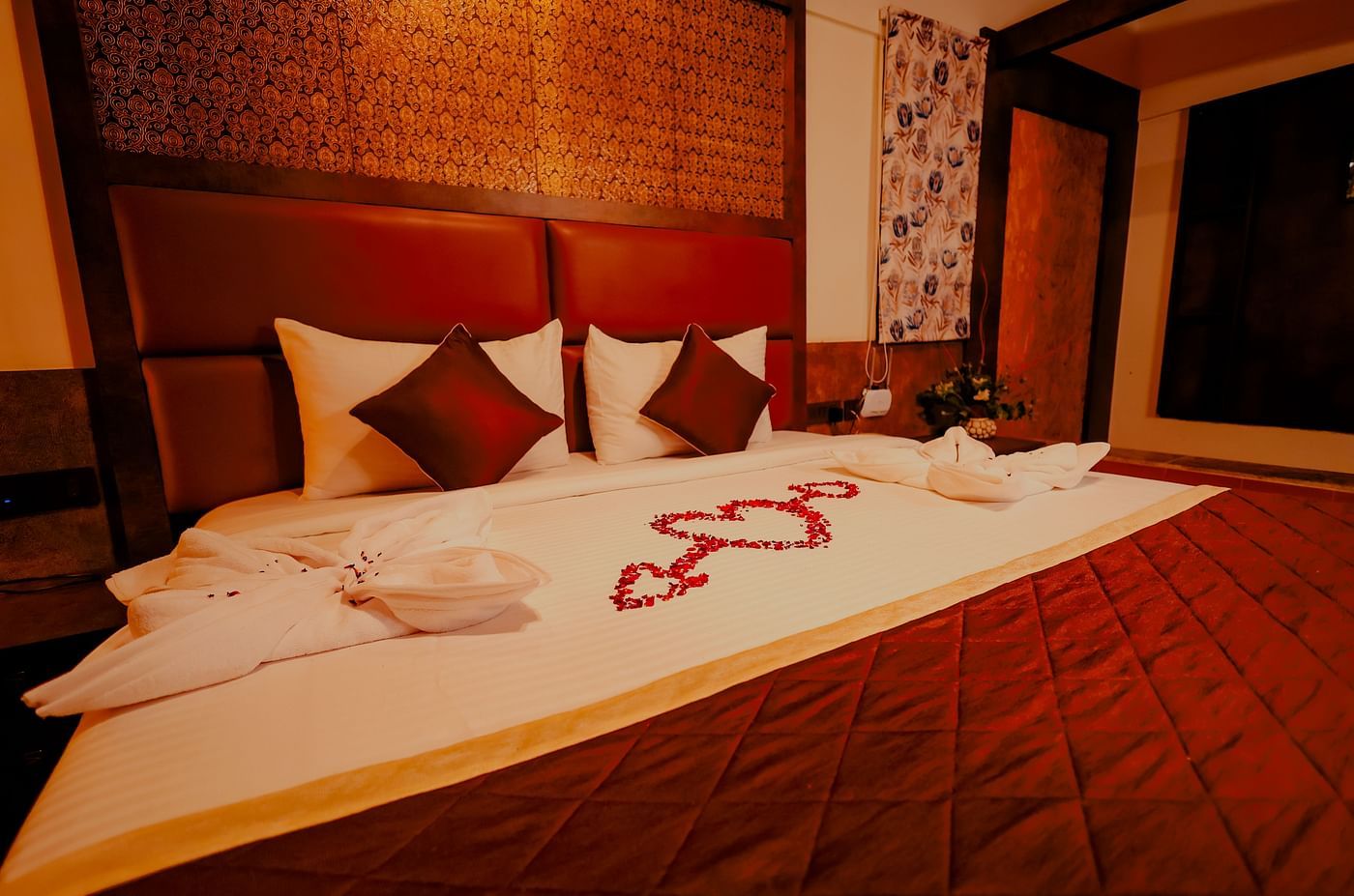 A neatly made bed with decorative towels and flowers in a room at Nirantara Resort & Spa