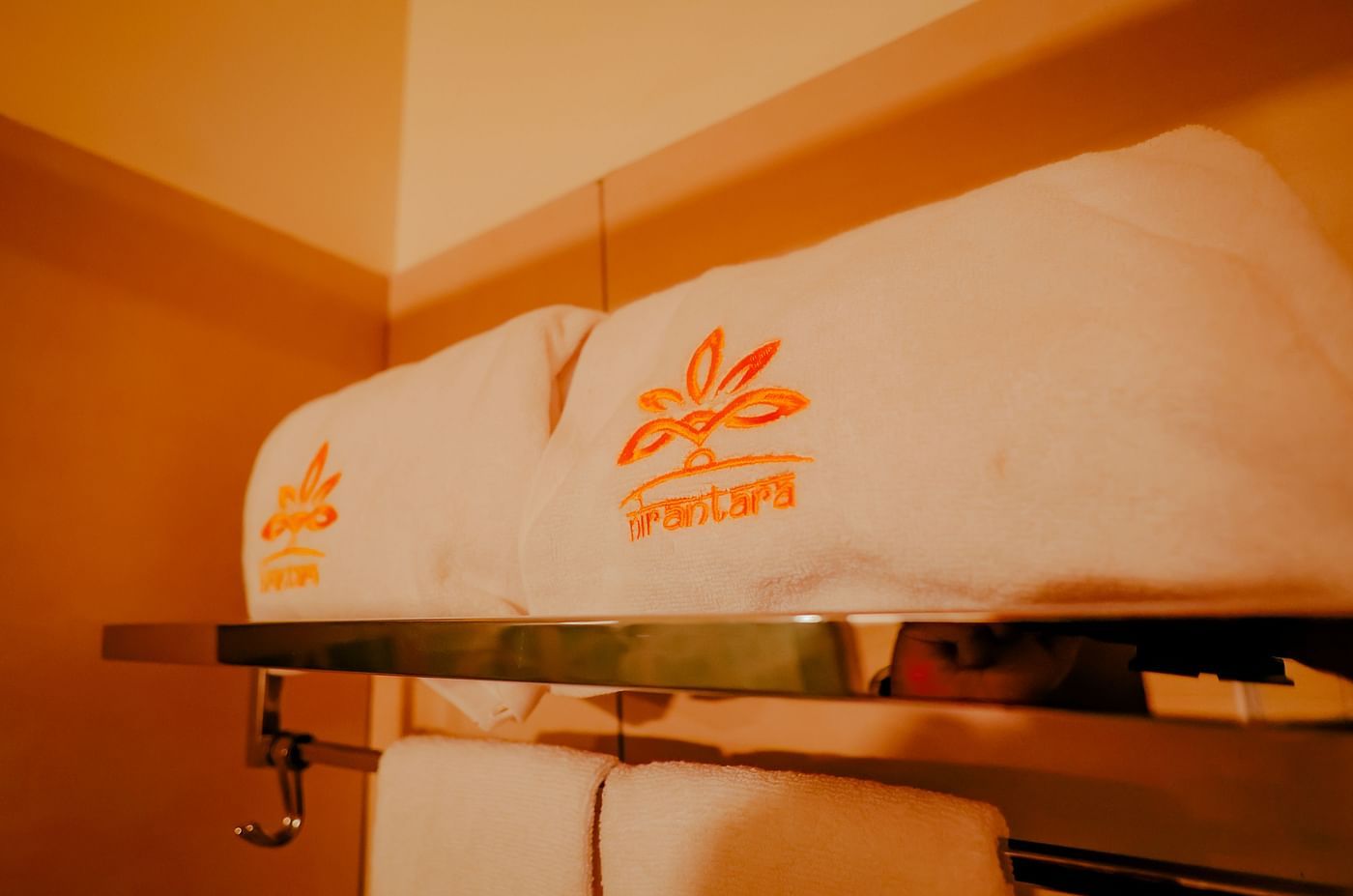 Close-up of a wall-mounted air-conditioning unit and towels at Nirantara Resort & Spa.
