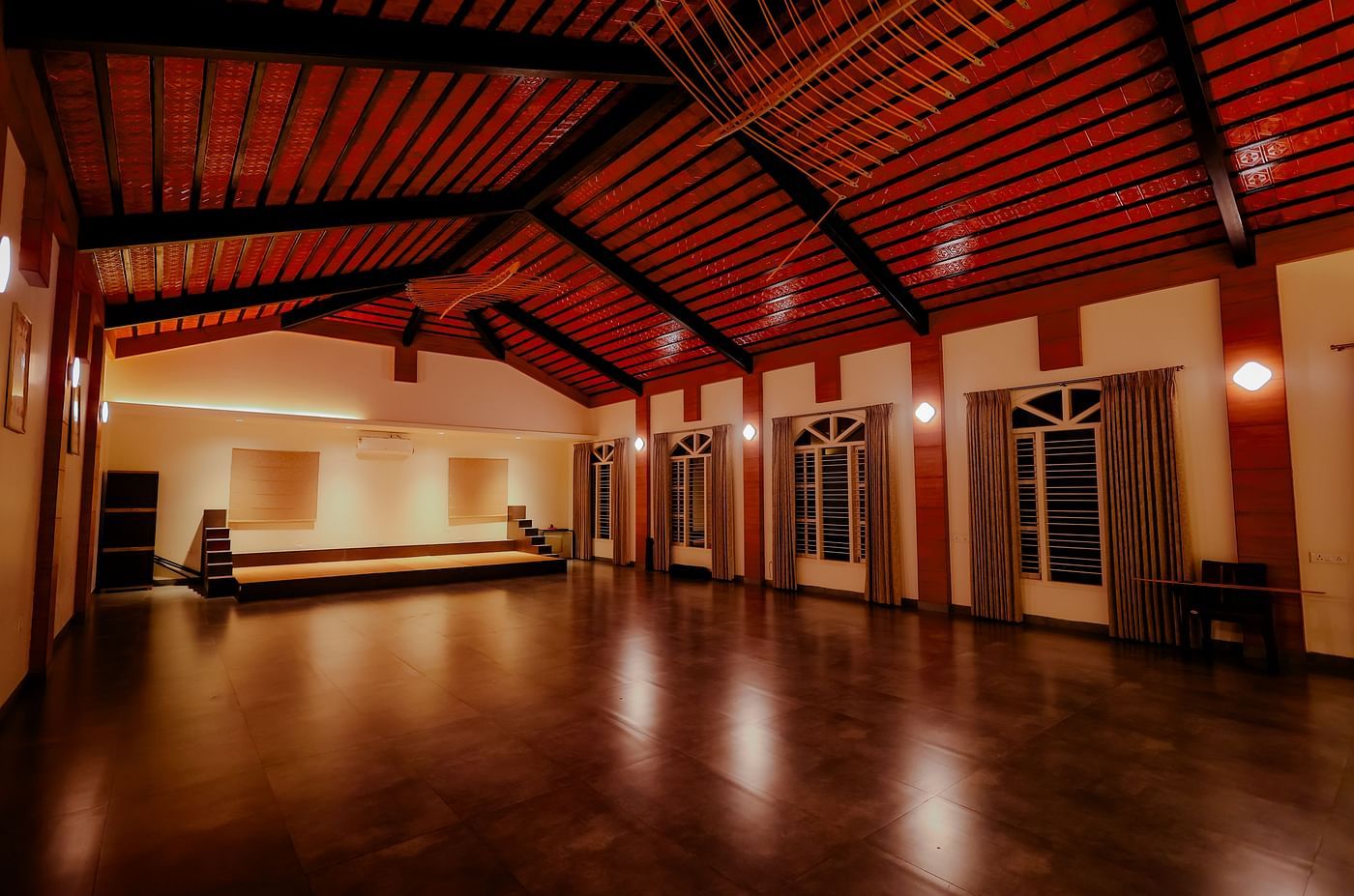 An empty event space or hall with a high ceiling and wooden floor at Nirantara Resort & Spa.