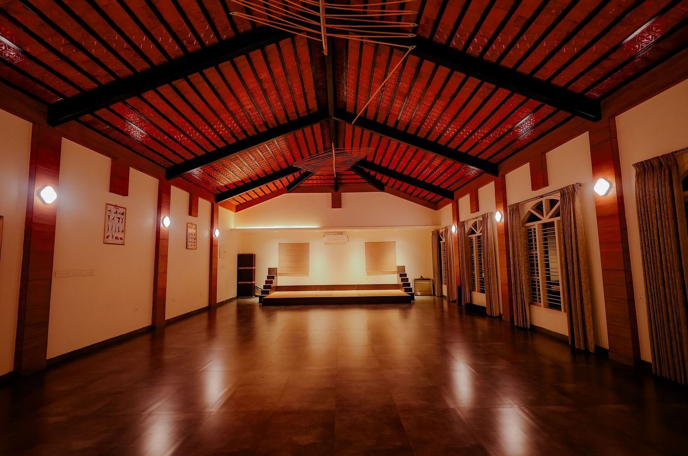 An empty event space or hall with a high ceiling and wooden floor at Nirantara Resort & Spa.