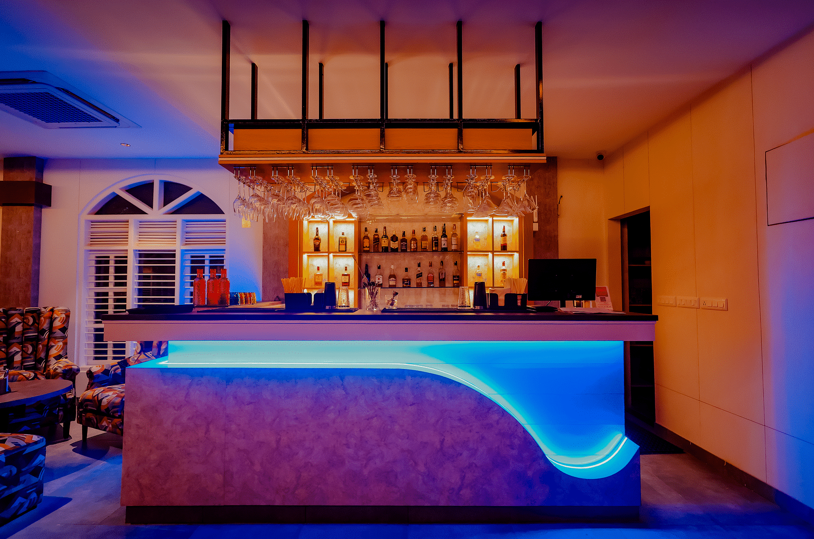The stylish bar area at Nirantara Resort & Spa, featuring modern lighting, comfortable seating, and a wide selection of beverages.