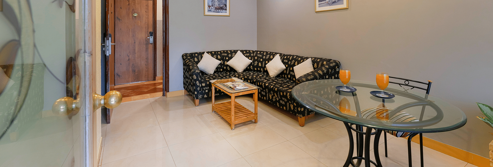 A seating area in our Suite in Bangalore with a glass table, a chair and a comfortable couch - Cross Roads Inn, Bengaluru