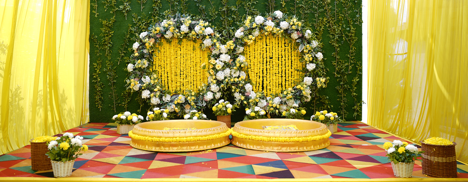 Brij Eternity, Vrindava |  A stage with floral backdrops, golden seating, and vibrant yellow drapery for wedding ceremonies.