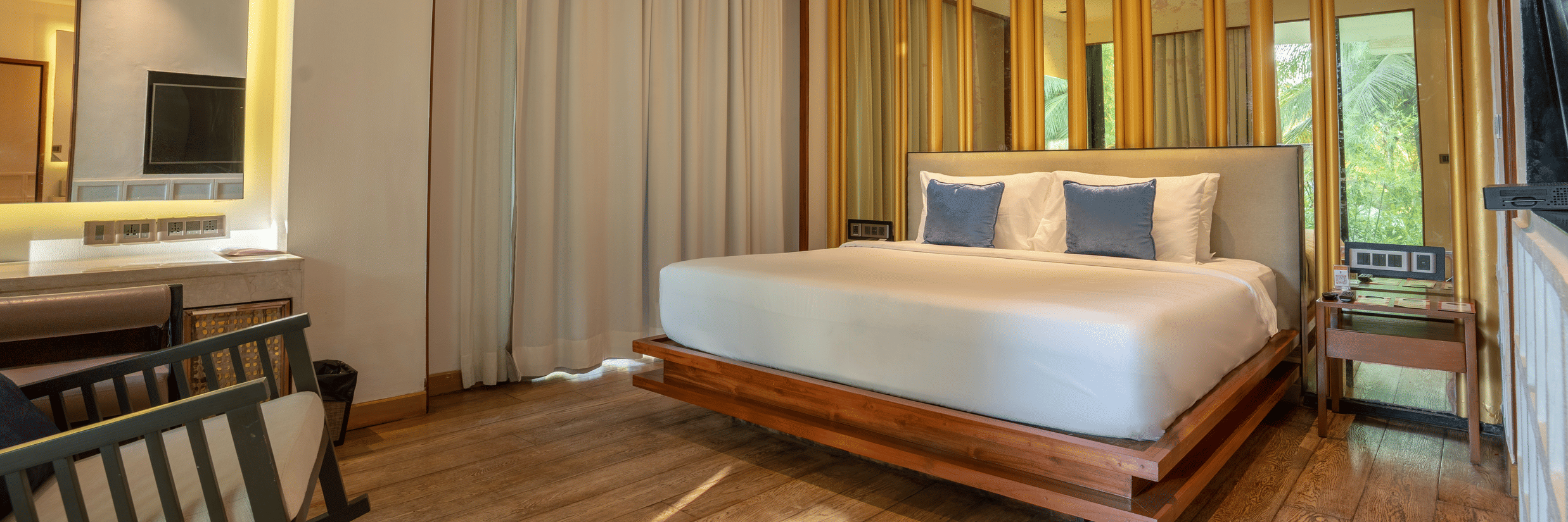 A contemporary bedroom at Azaya Beach Resort Goa featuring a floating wooden bed, timber wall panelling, and soft neutral tones.