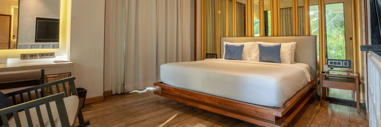 A contemporary bedroom at Azaya Beach Resort Goa featuring a floating wooden bed, timber wall panelling, and soft neutral tones.