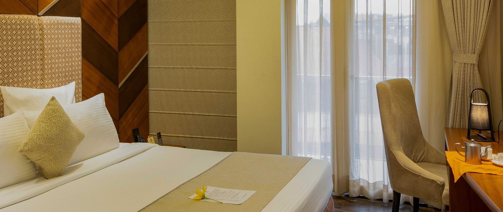 Image of Coral Suite at Coral Reef Hotel and Spa featuring a plush bed placed against a patterned wall next to the balcony door and a work desk near it