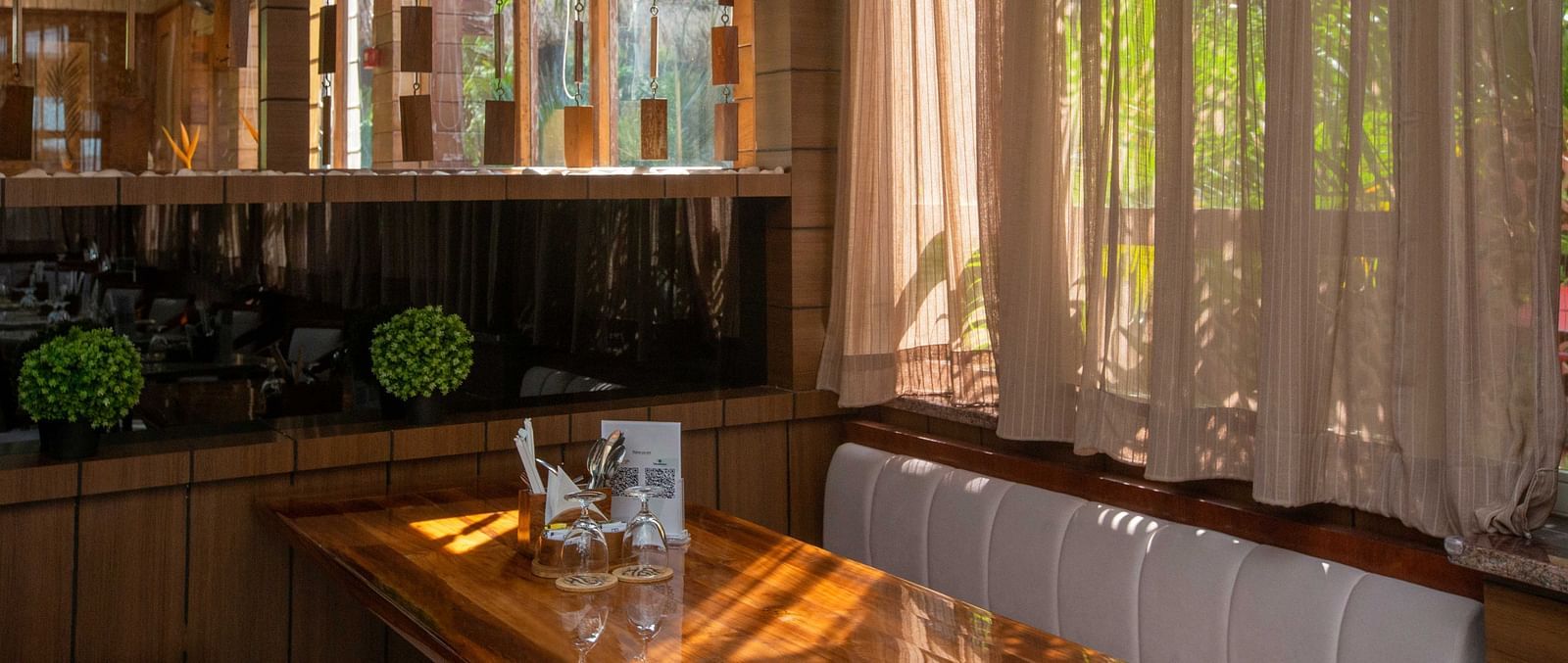 5th Bistro Cafe and Bar at Coral Reef Resort & Spa, Havelock featuring a stylish and modern area with sheer curtains letting in natural light. The space is lush with tropical plants, creating a relaxed yet sophisticated vibe - Coral Reef Resort & Spa, Have