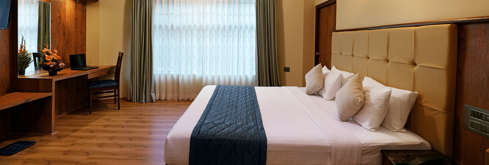 An Executive Room with a large bed, wooden decor, and natural light - Cross Roads Inn, Bengaluru