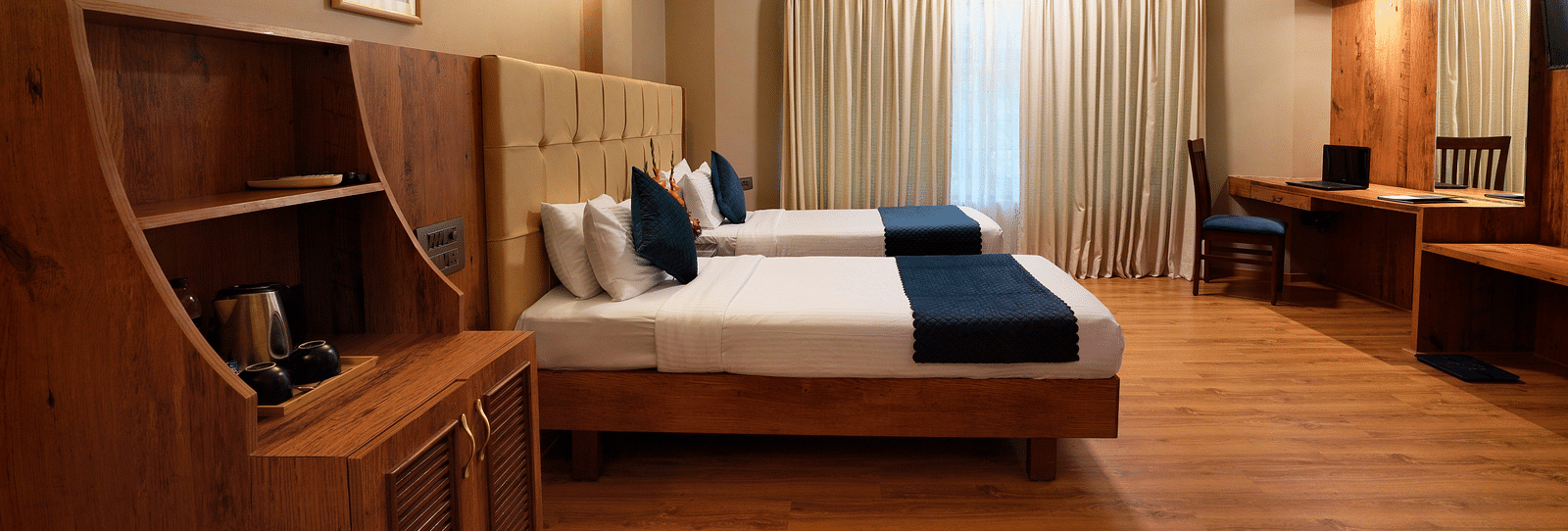 A spacious Executive Room with twin beds and a work desk - Cross Roads Inn, Bengaluru