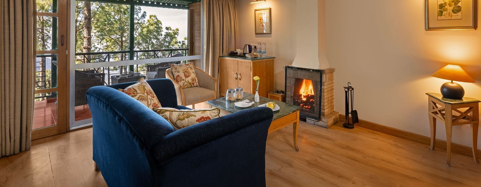 Premium Cottage sitting area with a comfy sofa, a view through window and fireplace in front of sofa at Baikunth resort, kasauli.