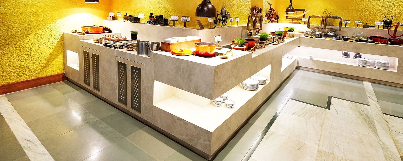 A well-arranged buffet line in a room with yellow walls and wooden ceiling at Tara, Comfort Hotel in Hyderabad - Ramoji Film City.